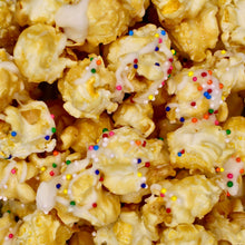 Load image into Gallery viewer, blonde caramel popcorn with white chocolate frosting drizzle and rainbow sprinkles. Kids gifts/ foods. All natural.
